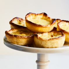 small pies are arranged on a white cake plate