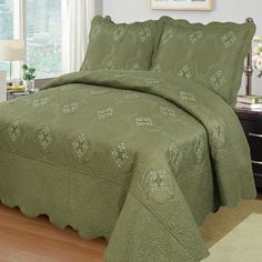 a bed with a green bedspread and matching comforter set in a bedroom