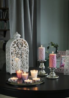 there are candles on the table with pictures in front of them and a birdcage