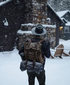 a man walking in the snow with a backpack on his back and hat over his head