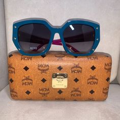 Brand New. Authentic Mcm Dual (Blue And Purple) Sunglasses. Frame Is Squared Butterfly Shape With Gold Studs To Outline. The Mcm Brand Logo On Each Temple. Lens Is Like Smoke Color. I Love The Flair And Mixture Of Colors On These Sunglasses. Very Classy And Compliments The Wardrobe. Size: Adult - 55/16/140 (Eye/Temple/Bridge). Comes With The Mcm Case And Cleaning Cloth Luxury Blue Sunglasses With Uva Protection, Designer Blue Sunglasses With Gradient Lenses, Formal Blue Sunglasses With Tinted Lenses, Formal Blue Tinted Sunglasses, Blue Sunglasses With Uv Protection For Formal Occasions, Formal Blue Sunglasses With Uv Protection, Designer Purple Sunglasses With Tinted Lenses, Designer Purple Sunglasses With Gradient Lenses, Designer Purple Tinted Sunglasses