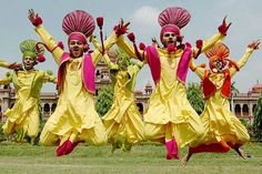 group of people dressed in yellow and pink dancing on grass