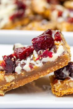 three pieces of dessert sitting on top of a white plate with cranberry toppings