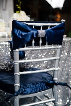 a silver chair with a blue bow on it's seat and sequin table cloth