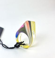 a multicolored ring is tied to a black string on a white background with a tag