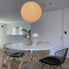 a white table with two chairs and a lamp hanging from it's center point