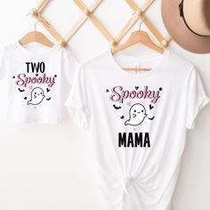 two spooky mama shirts hanging on a clothes rack next to a straw hat