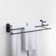 two towels are hanging on a towel rack in the bathroom, one is black and the other is white