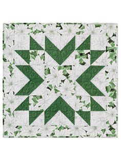 a green and white quilt with an arrow design on the center, surrounded by leaves