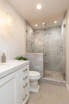 a bathroom with a walk in shower next to a white toilet and sink under two lights