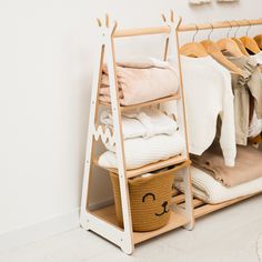 an organized closet with clothes hanging on the rack and a basket full of sweaters