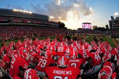 a group of football players standing on top of a field in front of a crowd