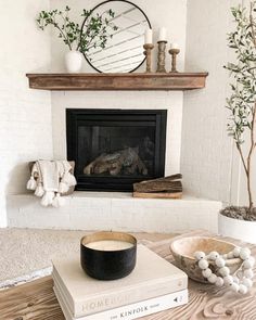 a living room with a fire place and books on the coffee table in front of it