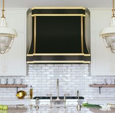 a kitchen with marble counter tops and white cabinets, hanging lights over the sink area