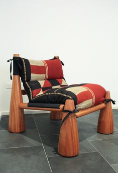 a chair that is sitting on some kind of wood with a black and red cushion