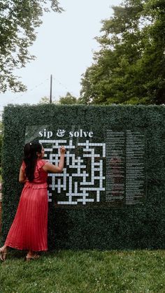 a woman in a red dress standing next to a large sign with writing on it