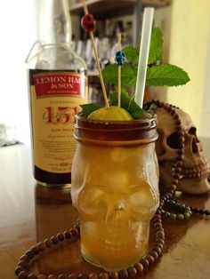 a glass jar filled with lemon and limeade next to a skull head