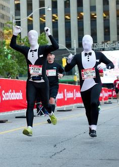 two men in tuxedos are running down the street with their arms in the air