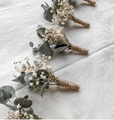 three bouquets of flowers are lined up on a white tablecloth with green leaves