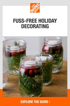 four glass jars filled with red berries and greenery