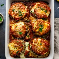 a casserole dish with meatballs and sauce in it on a blue table