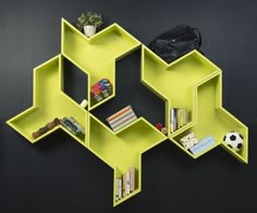 a yellow shelf with books and other items on it in front of a black wall