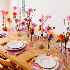 a wooden table topped with plates and vases filled with flowers