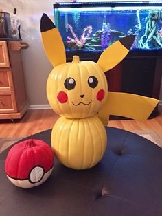 a pikachu pumpkin sitting on top of a table next to a pokemon figurine