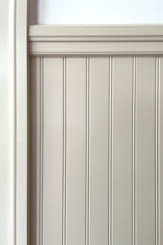 a cat is sitting on the floor in front of a wall with vertical striped paneling