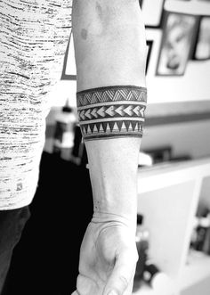 two people holding hands with tattoos on their arms and wristbands in black and white