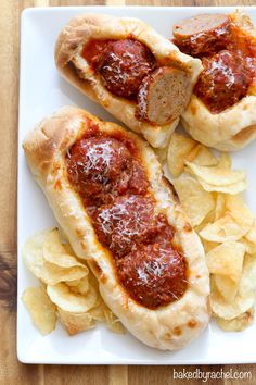 two hot dogs with ketchup and chips on a white plate