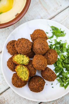 a white plate topped with meatballs and parsley on top of a wooden table