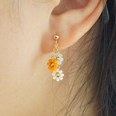 a close up of a person's ear wearing earrings with flowers hanging from them