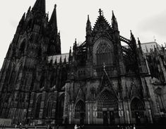 black and white photograph of the front of a large cathedral with people standing in front