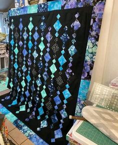 a black and blue quilt hanging on a wall next to a sewing machine in a room