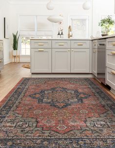 a large rug is in the middle of a kitchen with white cabinets and gray cupboards