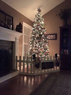 a christmas tree is lit up in the corner of a living room with a fireplace