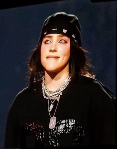 a young woman wearing a black hat and shirt with chains on it's neck