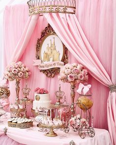 a table topped with lots of cake and desserts next to a pink drapes