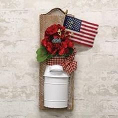 an american flag hangs on the wall next to a white canister with red flowers