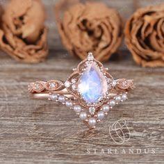 a white opal and diamond ring on a wooden table with roses in the background