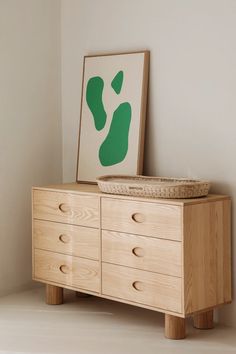 a wooden dresser sitting next to a painting on the wall