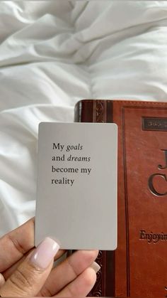 a person holding up a book with the words my goals and dreams become my reality