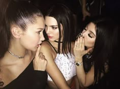 three young women standing next to each other with their hands on their face and looking at the camera