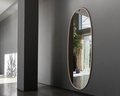 an oval mirror on the wall in a room with concrete flooring and white walls