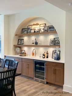 a dining room table and chairs in front of a built - in wine rack with pictures on it