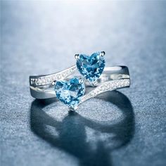 two heart shaped blue topazte rings with diamonds on the sides, set in white gold