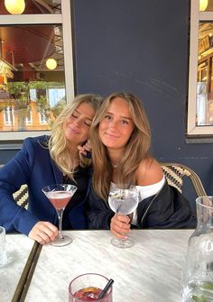 two women sitting at a table with drinks