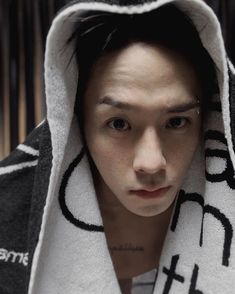 a young man wearing a hooded sweatshirt and looking at the camera with an intense look on his face