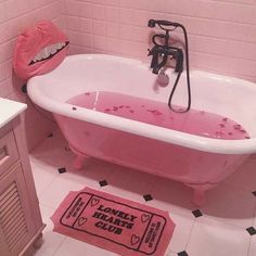 a pink bath tub sitting inside of a bathroom next to a rug on the floor